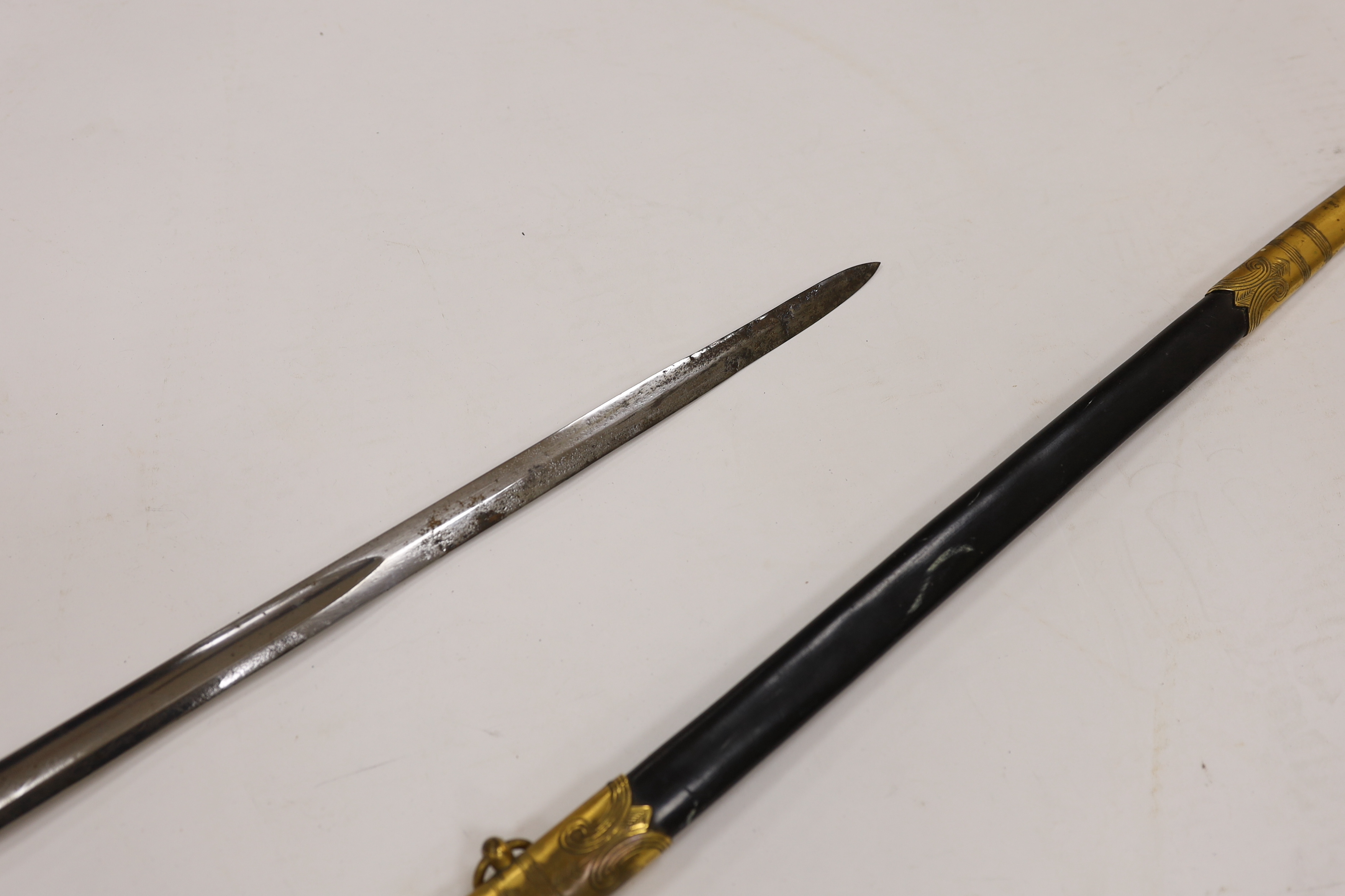 A World War I naval sword with folding guard engraved J.W. Collett R.N., regulation gilt hilt and scabbard mounts, the blade has been refinished and furniture regilded, with bullion dress knot, blade 78.5cm